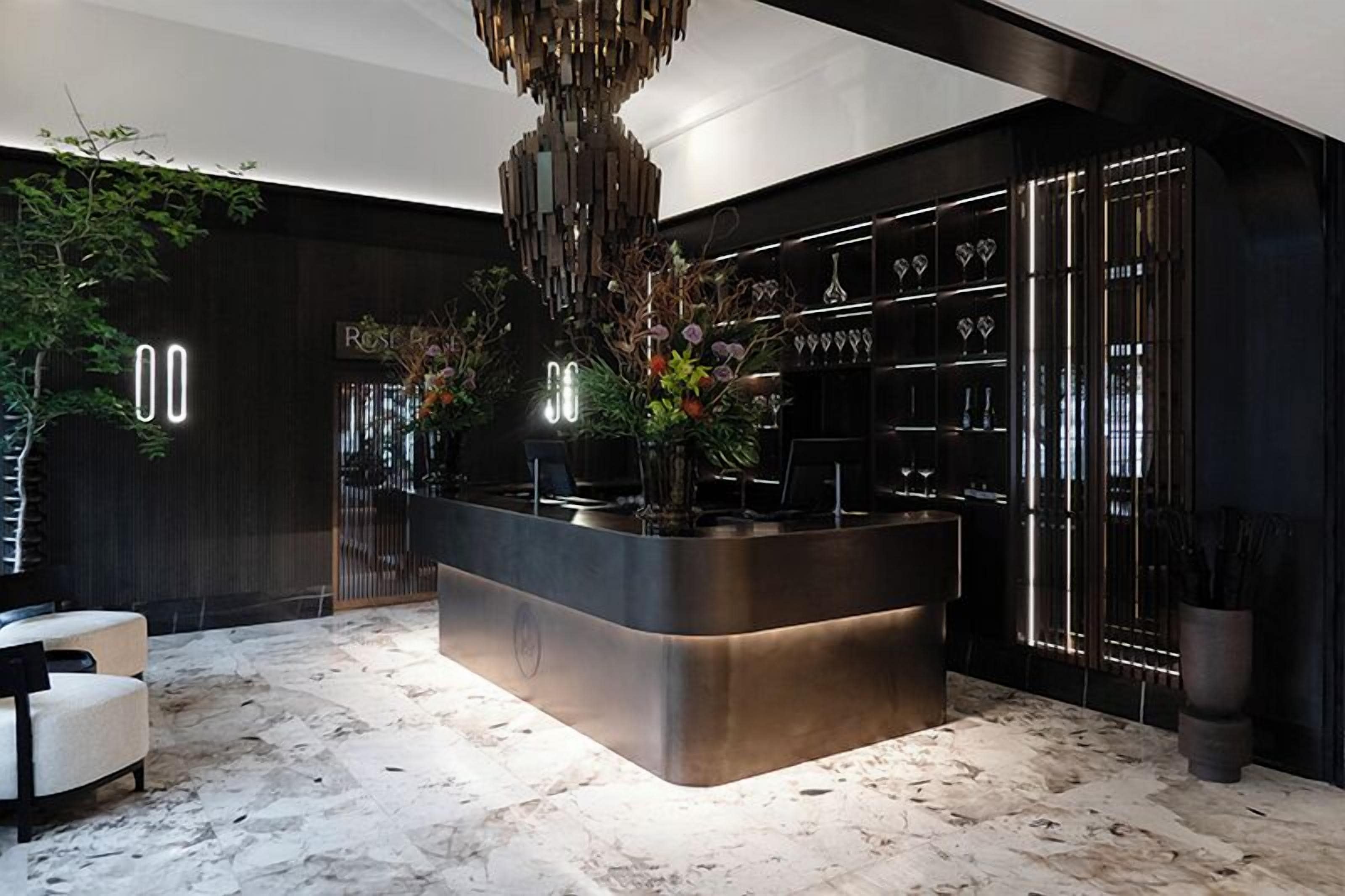 A modern bar area with a central island, a chandelier, and a wine rack.