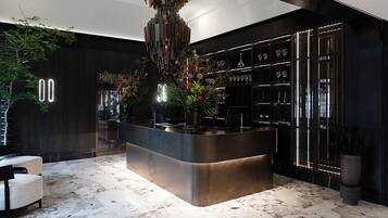 A modern bar area with a central island, a chandelier, and a wine rack.