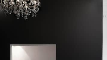 A modern bathroom with a black bathtub, marble wall, and a chandelier.