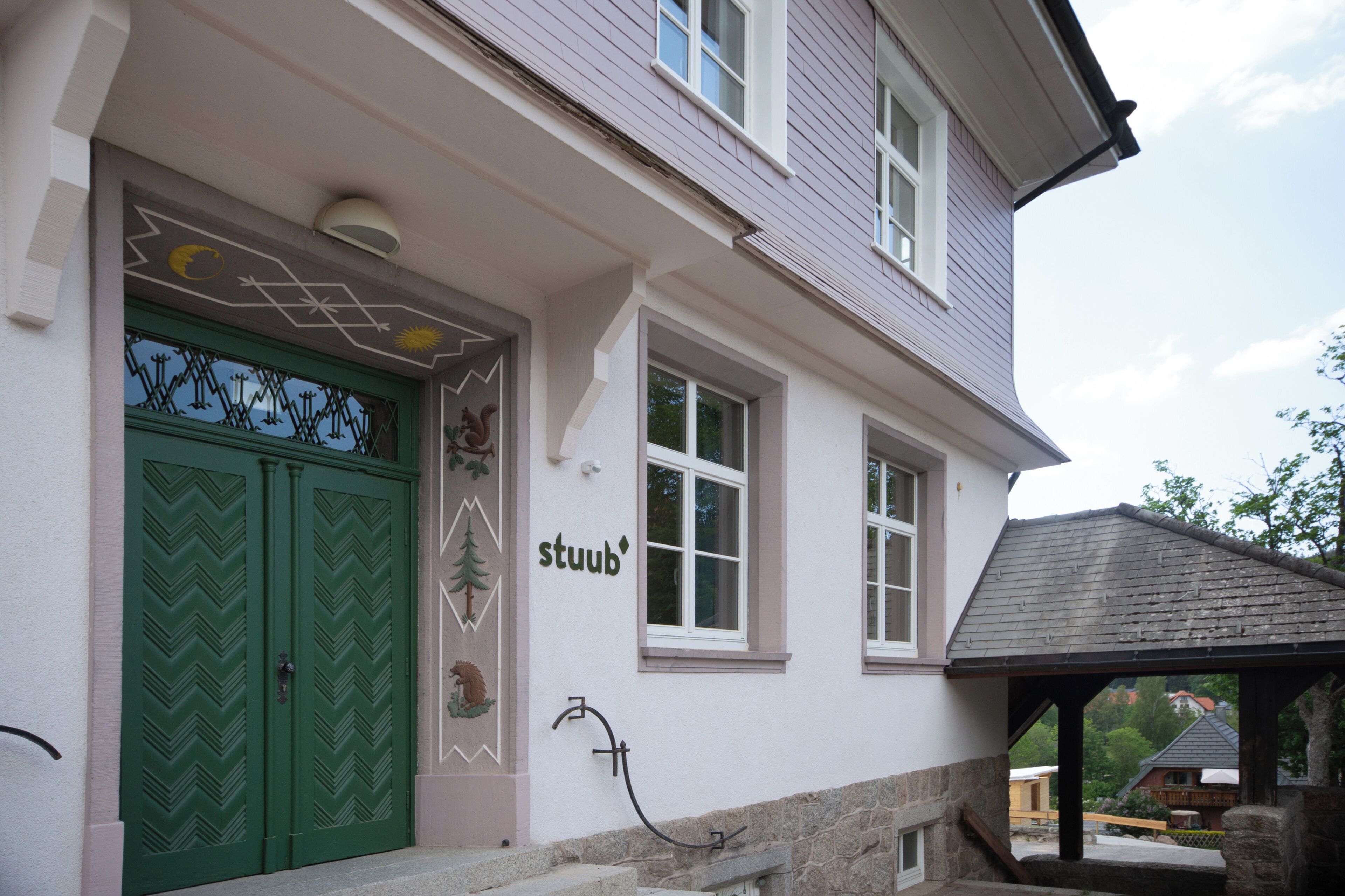 A building with a green door, a sign reading 'stuub,' and a stone bench outside.