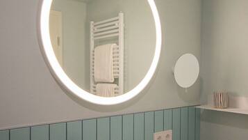 A bathroom with a round mirror, a sink, and a towel rack.