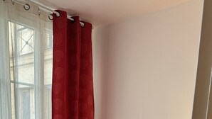 A bedroom with a bed, white curtains, and a window.