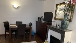A living room with a dining table, chairs, a fireplace, and a television.