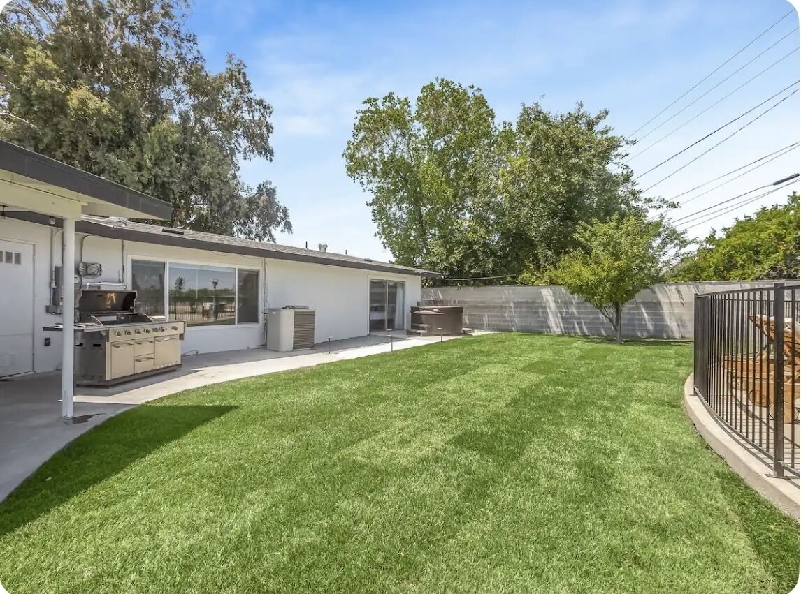 A modern house with a covered patio, a well-maintained lawn, and a fenced backyard.