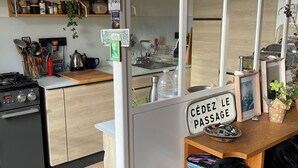 Una cucina con mobili in legno, un fornello e un lavello. Si vedono diversi utensili da cucina e un cestino.
