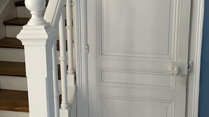 Una porta bianca dal design semplice, una scala in legno con ringhiere bianche e un muro blu.