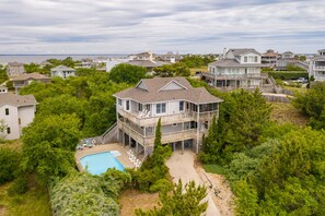 A multi-story house with a pool, surrounded by lush greenery and other residential buildings. - Sun Realty cozy cottage between the ocean and the sound in Duck, NC (Duck)