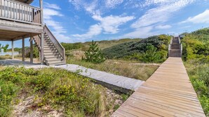 Ein hölzerner Steg führt zu einem Gebäude aus Holz mit einer Treppe.