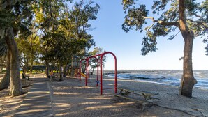 A beachside park with a wooden walkway, benches, and playground equipment. - Water views and a fenced-in yard at Meehan Cottage in Colington Harbour (Kill Devil Hills)