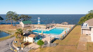 A beachfront property with a large swimming pool, a lighthouse, and a pier. - Water views and a fenced-in yard at Meehan Cottage in Colington Harbour (Kill Devil Hills)