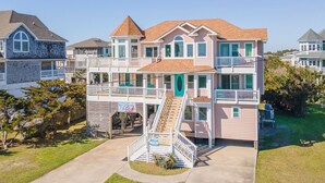 Une maison à plusieurs étages avec un escalier central, un balcon et une véranda à l’avant.