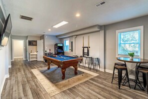 Quarto com mesa de bilhar, bar e dardos.