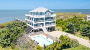 A multi-story beachfront house with a large balcony, a swimming pool, and a dock extending into the water. - Soundfront serenity with a private dock at Blue Horizon in Salvo! (Salvo)