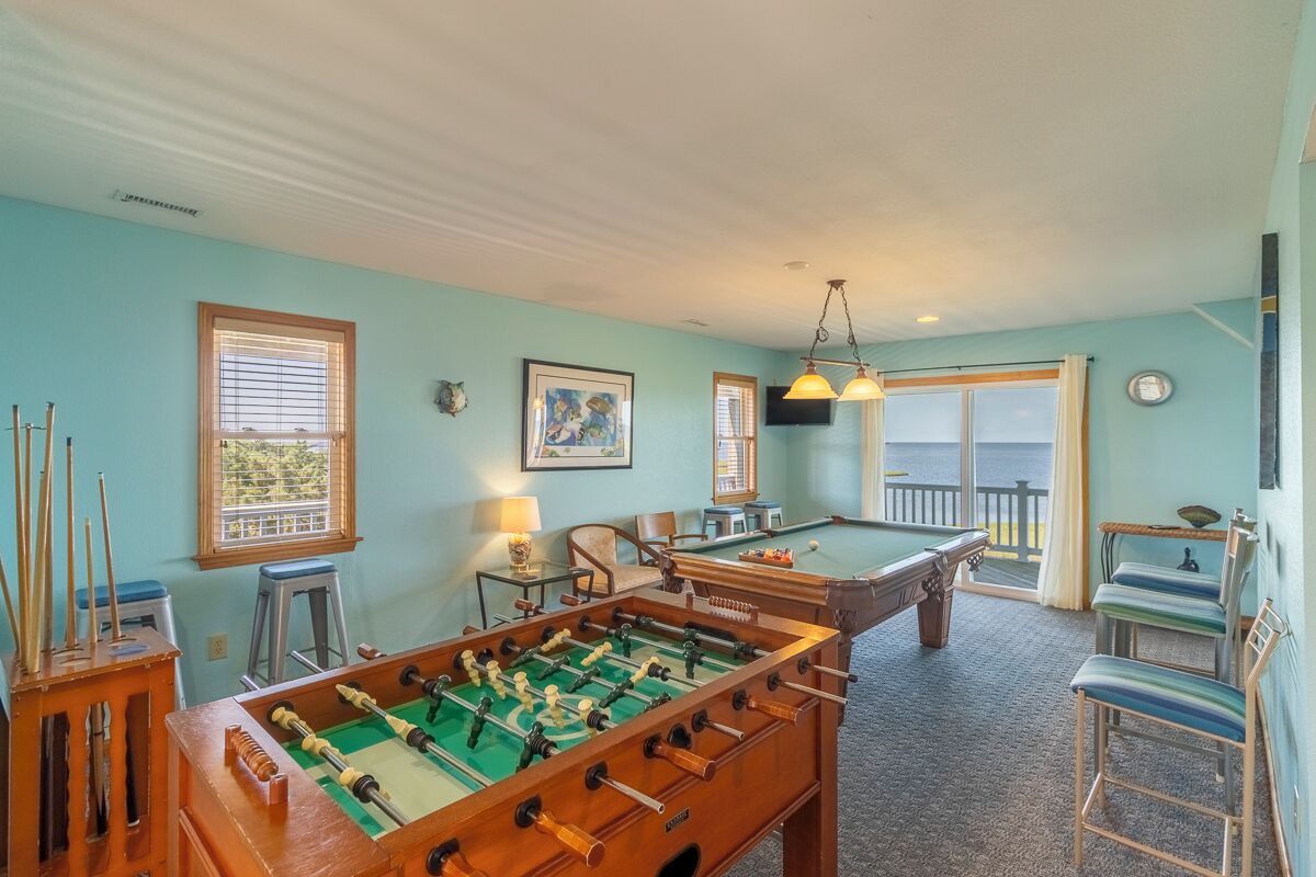 Una habitación con mesa de futbolín, mesa de billar y vistas al exterior.