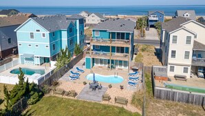 A residential area with a large house featuring a swimming pool and multiple balconies. - Sun Realty ocean and sunrise views from Making Waves in Kill Devil Hills, NC (Kill Devil Hills)