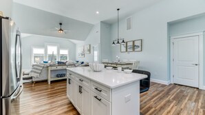 Une cuisine spacieuse dotée d’un îlot central, de meubles blancs et d’un plancher en bois.
