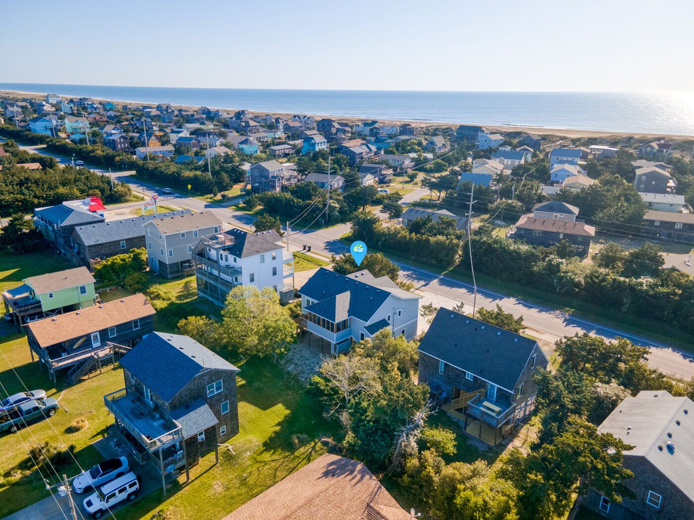Vista aérea de una zona residencial con casas, una carretera y una playa al fondo.