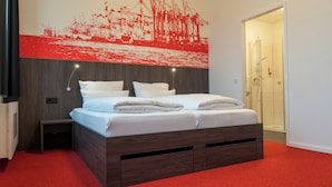 Un dormitorio moderno con una cama de madera, ropa de cama blanca, una alfombra roja y un cuadro abstracto rojo grande en la pared.