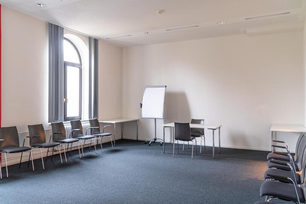 Una sala de conferencias con una pizarra, una mesa larga y varias sillas.