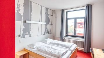 A room with a bed, a small table, and a window with curtains.