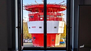 Una gran estructura cilíndrica roja y blanca, probablemente un tanque elevado, vista a través de una puerta.