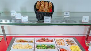 Un bufé con diversos alimentos, entre ellos pan, queso y verduras.