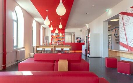 A modern interior with red seating, a kitchen area, and a reception desk.