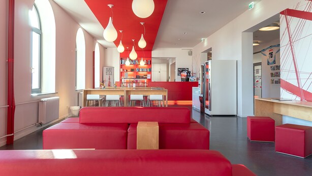 Un interior moderno con asientos rojos, una zona de cocina y un mostrador de recepción.