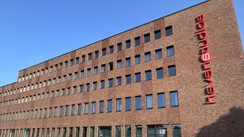 A modern brick building with multiple windows and a prominent red sign on the side.