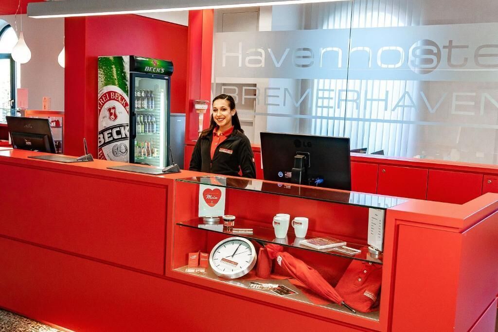 A red reception desk with a Beck's beer cooler, a clock, and a coffee display.