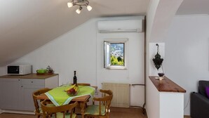 Un'area pranzo con un tavolo imbandito per quattro persone, un forno a microonde su un mobile, una finestra vista verde e un lampadario a sospensione.