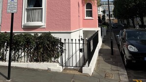 A pink building with a parking sign, a gated entrance, and a street lamp. - 2 single or 1 King bed in Notting Hill.. Super location for sightseeing London
 (London)