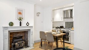 A modern kitchen with white cabinets, a built-in stove, and a fireplace with decorative items. - 2 single or 1 King bed in Notting Hill.. Super location for sightseeing London
 (London)