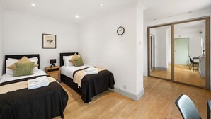 A modern hotel room with two beds, a small desk, a chair, and a large mirror. - 2 single or 1 King bed in Notting Hill.. Super location for sightseeing London
 (London)