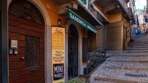 Vista de calle con una puerta de madera, un letrero que dice 'MINI MARKET' y una escalera que lleva a un edificio.