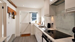 Une cuisine moderne avec des meubles blancs, une plaque de cuisson à induction noire et une fenêtre offrant une belle vue.