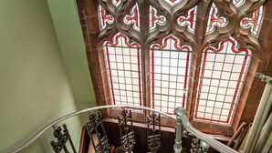 A spiral staircase with ornate metal railings and a brick wall with decorative stained glass windows. - The Old Sunday School & Vestry (Cromer)