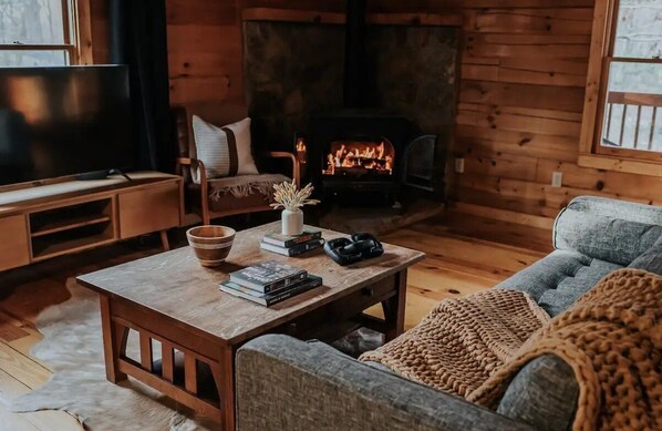 Ein gemütliches Wohnzimmer mit Kamin, Fernseher und einer bequemen Sitzecke.