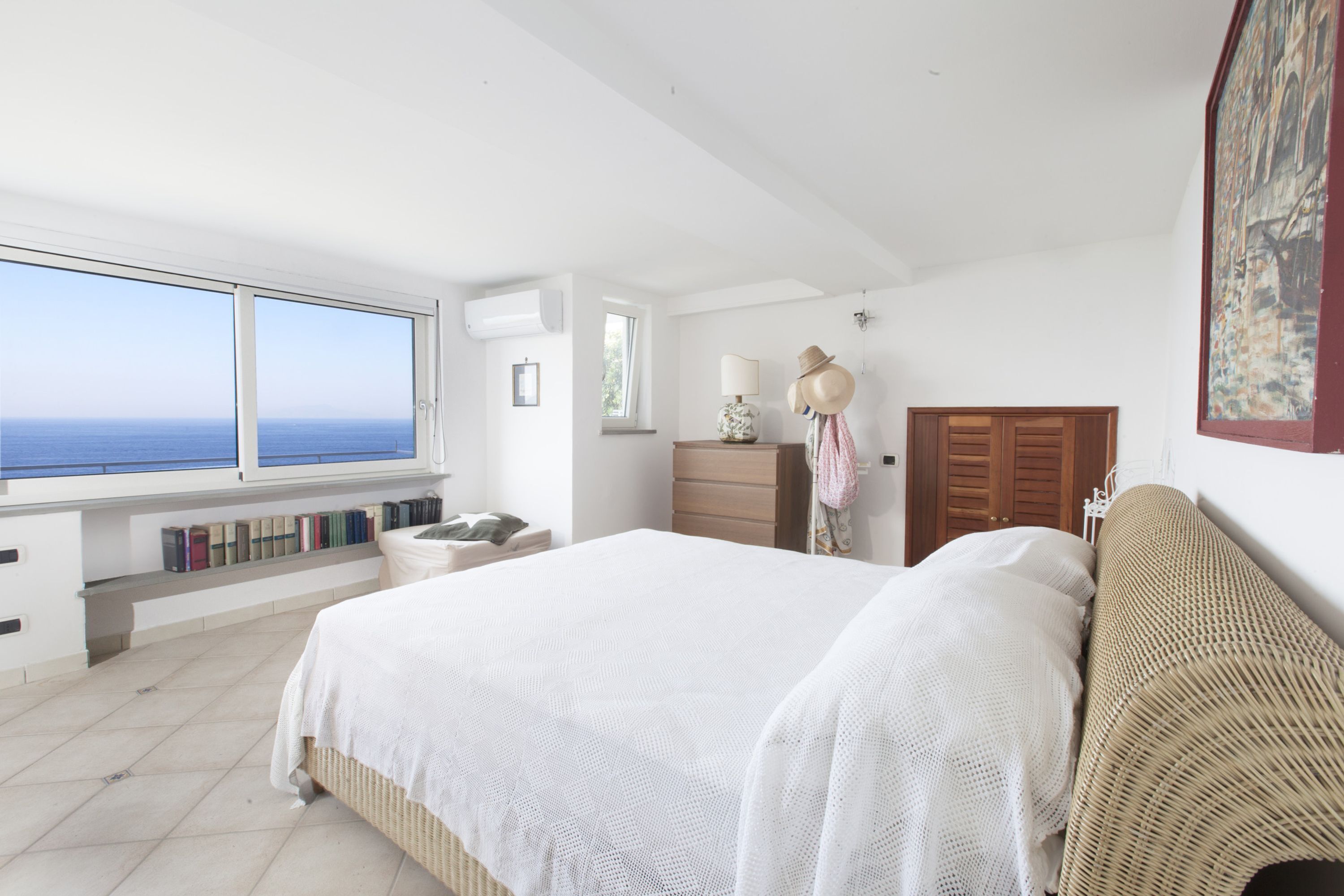 Un dormitorio con una cama grande, un aparador, un tocador y una ventana con vista al mar.
