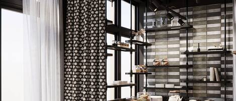 A modern kitchen with a wooden island, black chairs, and a patterned curtain.