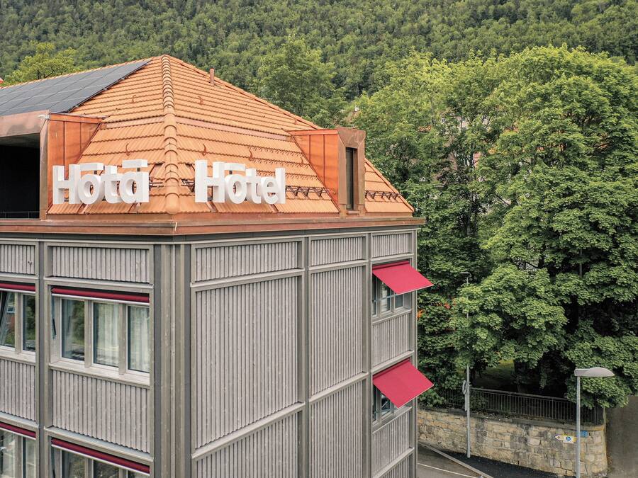 Un hôtel avec un toit recouvert de tuiles rouges et une enseigne sur laquelle on peut lire « Hôtel Hôtel ».