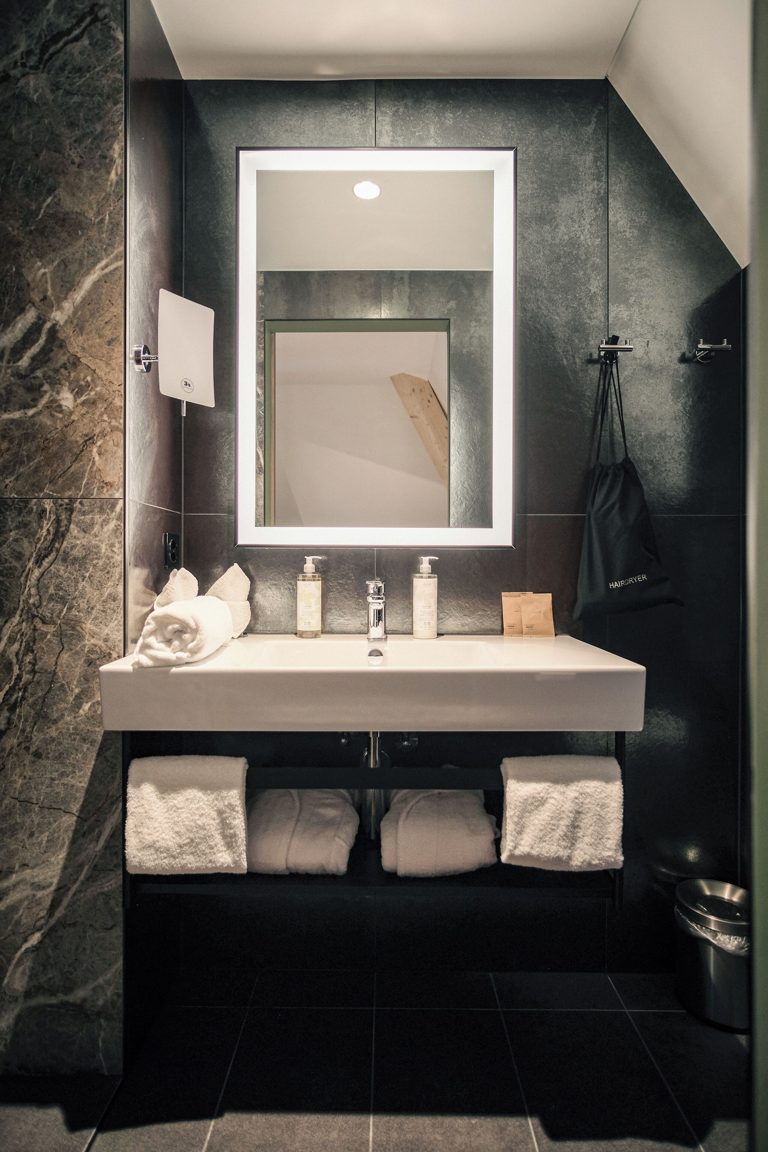 Un baño moderno con un espejo grande, un lavabo y dos toallas.