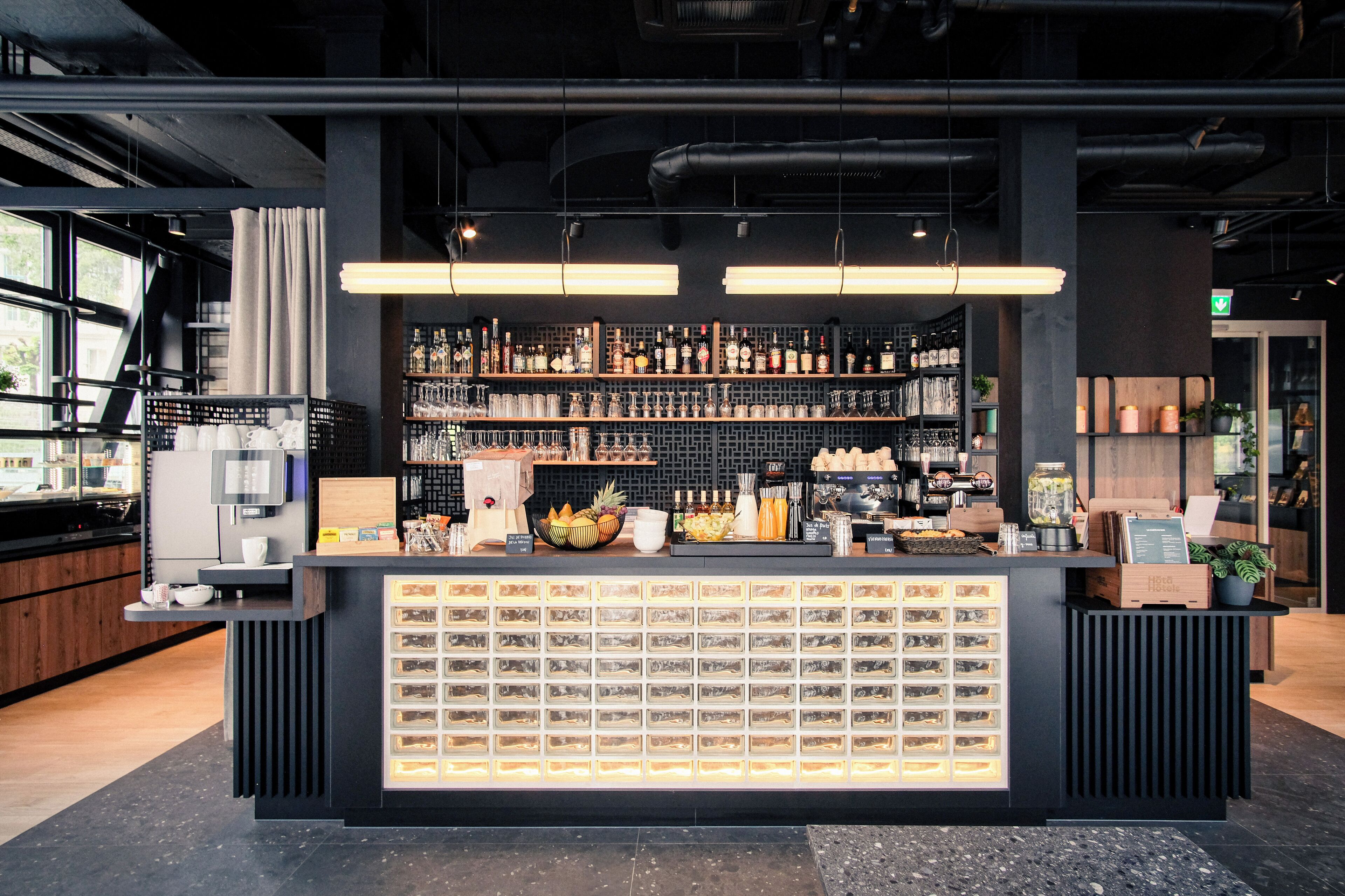 A modern bar area with a well-stocked shelf of beverages, a variety of snacks, and a display of neatly arranged bottles.