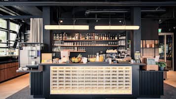 A modern bar area with a well-stocked shelf of beverages, a variety of snacks, and a display of neatly arranged bottles.
