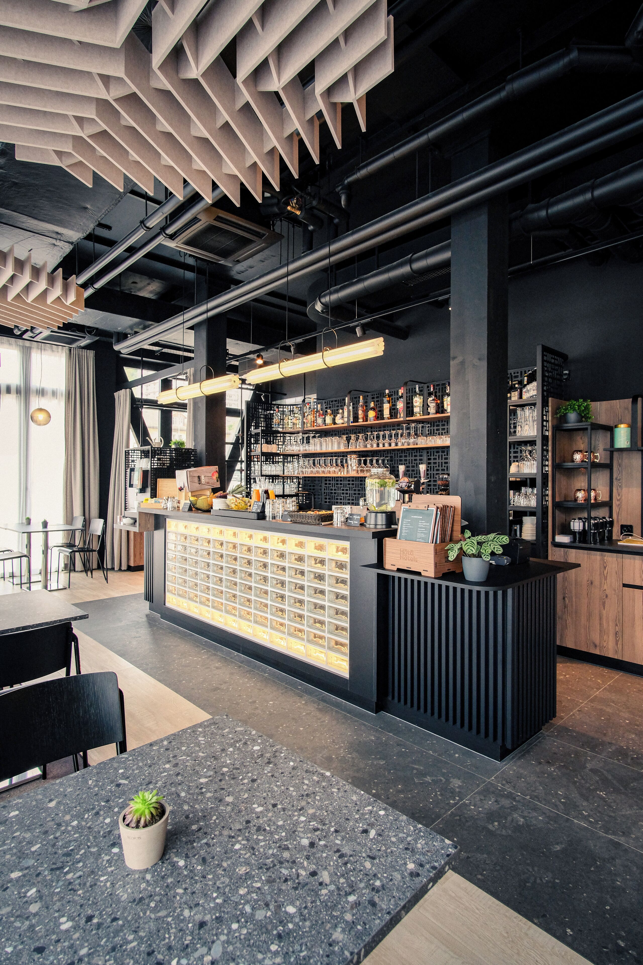 Een moderne bar met een toog, flessenplanken en een zithoek met een tafel en stoelen.
