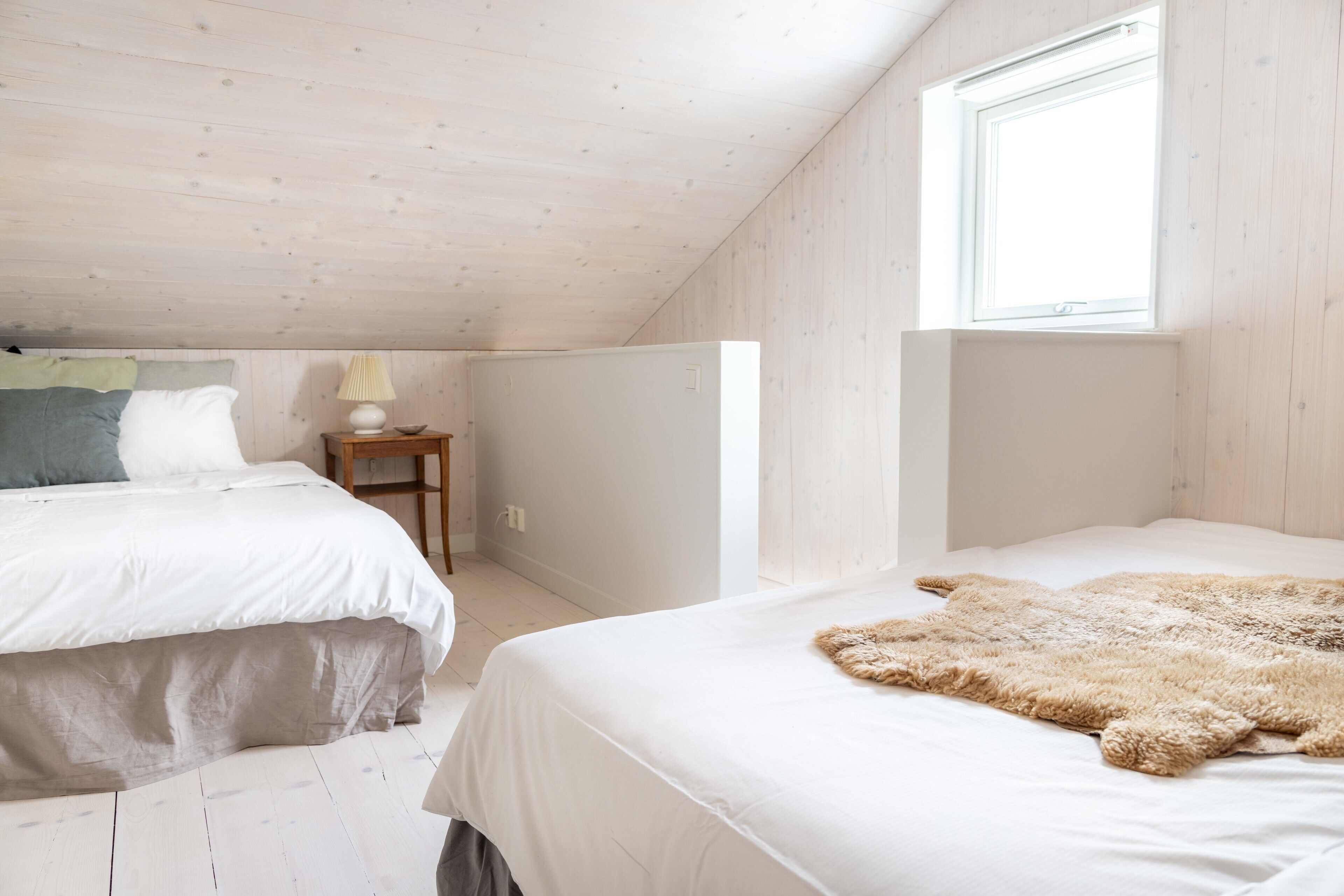 A bedroom with two beds, a window, and a lamp on a nightstand.