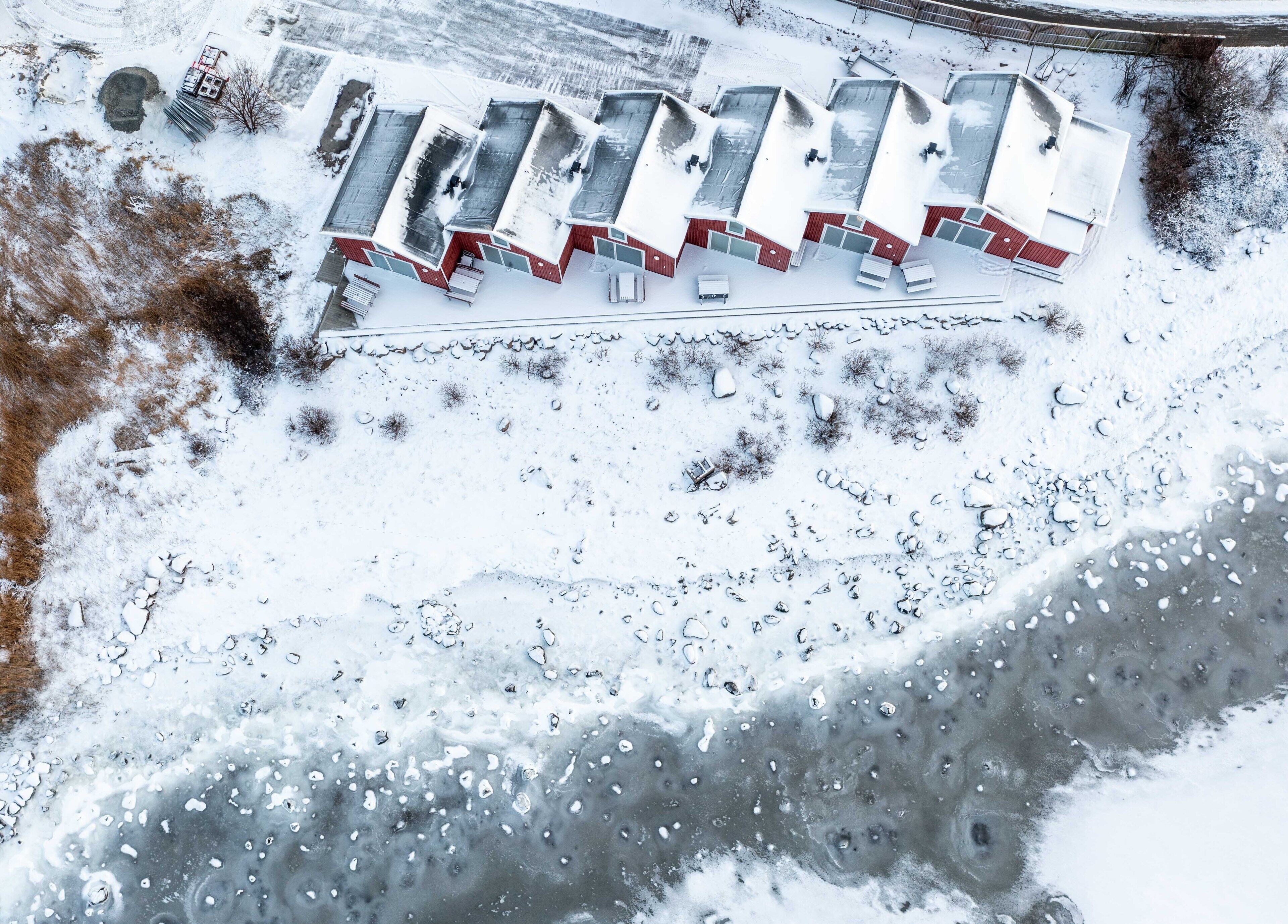 Un edificio con la neve, diverse stanze, un'area di parcheggio e un piccolo spazio esterno innevato.