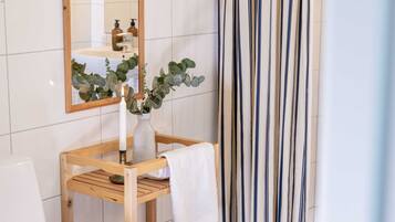 Un bagno con un mobile lavabo in legno, uno specchio, una pianta in vaso e una tenda a righe.