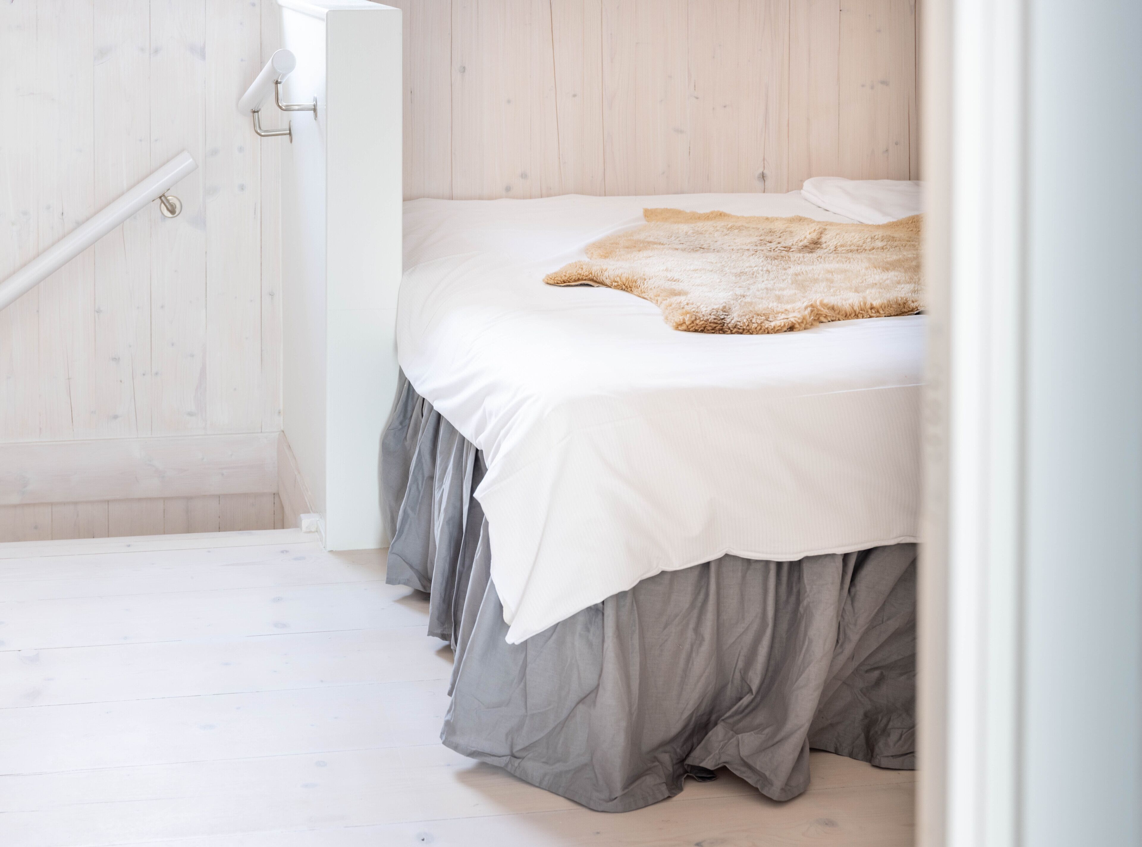 Une chambre à coucher avec un lit, un plancher en bois et un mur blanc.