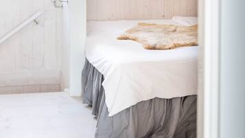 Une chambre à coucher avec un lit, un plancher en bois et un mur blanc.